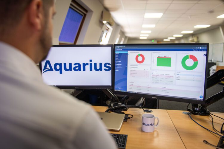 Aquarius IT Compliance Dashboard On Double Screen Computer